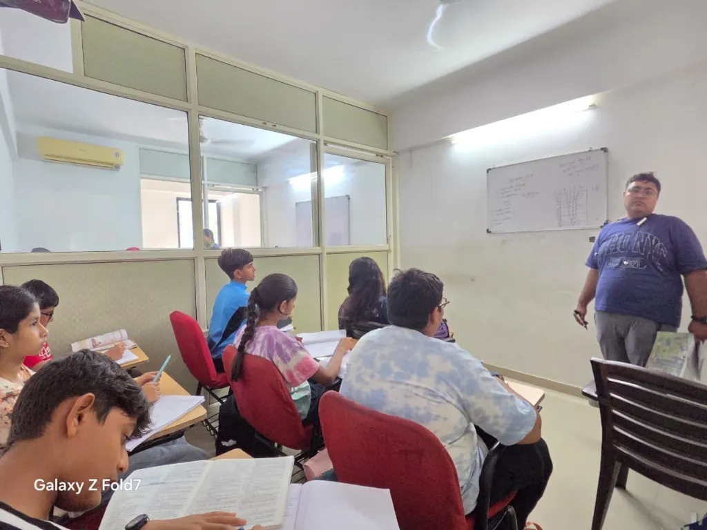 Abhishek Sir teaching mathematics and science equations on the whiteboard at NIMKOM